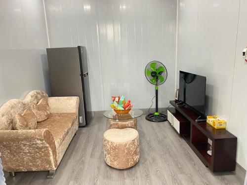 ein Wohnzimmer mit einem Sofa und einem TV in der Unterkunft Homestay Cô Hai Garden in Ấp Vĩnh Hưng