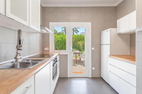 a white kitchen with a sink and a window at Casa a metros del Mar in Playa de Muro