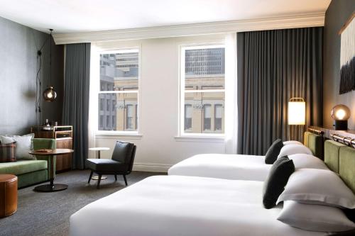 ein Hotelzimmer mit 2 Betten und einem Stuhl in der Unterkunft The Alexis Royal Sonesta Hotel Seattle in Seattle