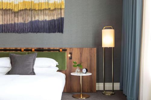 a bedroom with a bed and a table with a lamp at The Alexis Royal Sonesta Hotel Seattle in Seattle