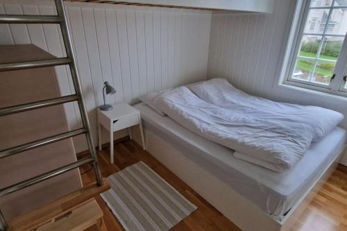a small bedroom with a bed and a ladder at Fjøsen - Bleik Beach in Bleik
