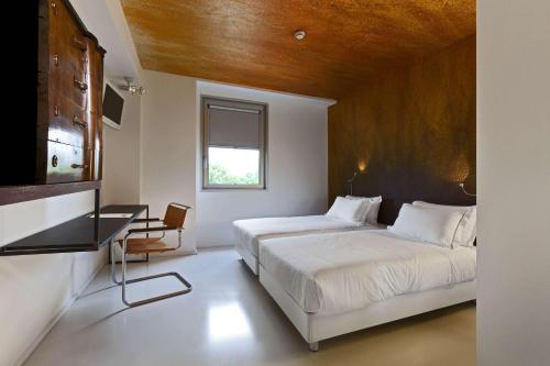 a bedroom with a bed and a desk and a window at Aiden by Best Western JHD Dunant Hotel in Castiglione delle Stiviere