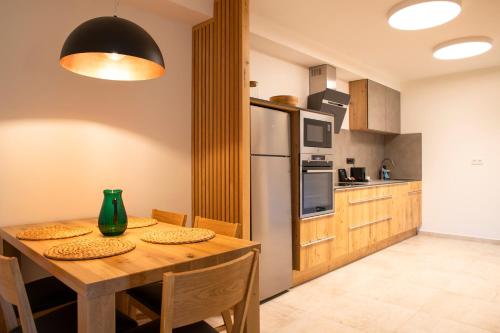 a kitchen with a wooden table and a refrigerator at Amenity Hotel & Resort Lipno in Lipno nad Vltavou