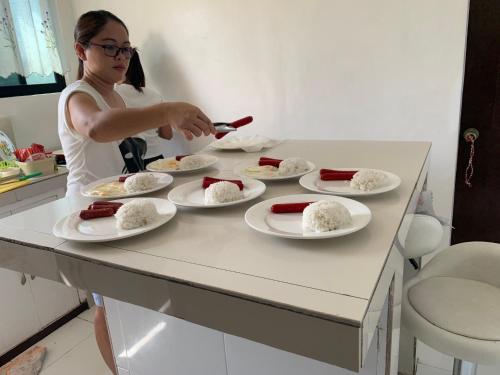 a woman is preparing food on a table with plates of food at LUNA OSLOB TRAVELLERS INN - Beach Front in Oslob