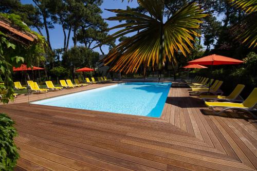 a swimming pool with lounge chairs and umbrellas at Hôtel The Originals Résidence de Rohan (EX RELAIS DU SILENCE) in Vaux-sur-Mer