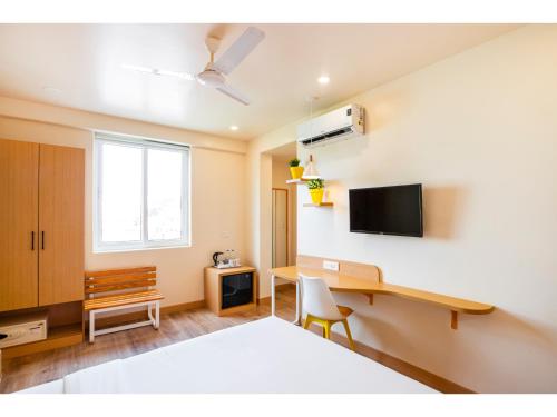 a bedroom with a bed and a desk and a tv at Bloom Hotel - HSR Club in Bengaluru