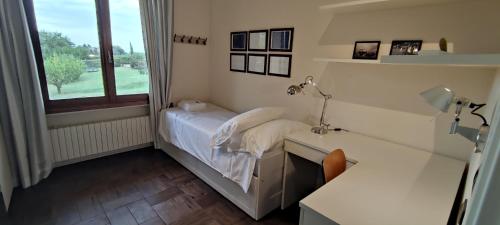 1 dormitorio con cama, escritorio y ventana en Casa in Locanda, en San Lazzaro di Savena