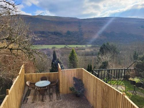 a table and chairs on a fence with a view at Mountain View Cottage sleep 6 sofabed quaint and quirky cottage in Ystalyfera