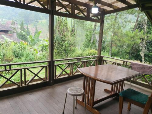 a wooden table and chairs on a balcony with a view at Aubrey Villa Ciwidey in Pengalongan