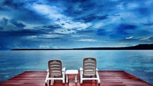 two chairs sitting on a dock next to the water at Jelly Sea Resort in Siquijor