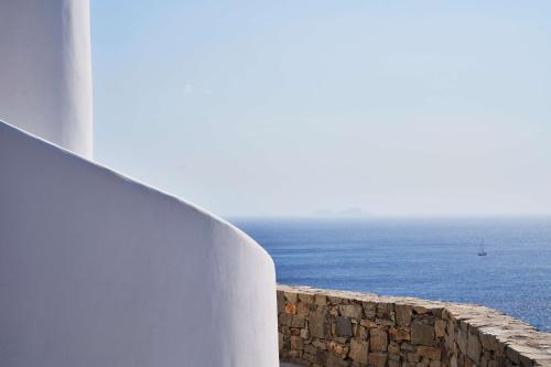 a stone wall with the ocean in the background at Radisson Blu Euphoria Resort, Mykonos in Kalo Livadi