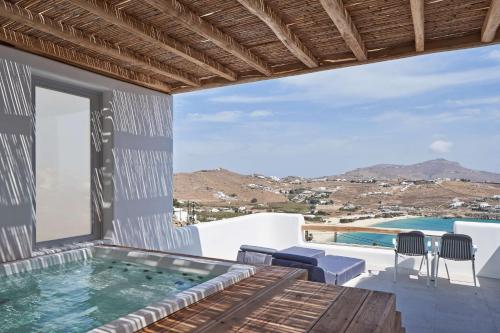 a villa with a plunge pool and a deck with chairs at Radisson Blu Euphoria Resort, Mykonos in Kalo Livadi