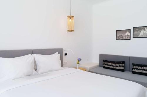 a bedroom with a large white bed and a couch at Radisson Blu Euphoria Resort, Mykonos in Kalo Livadi