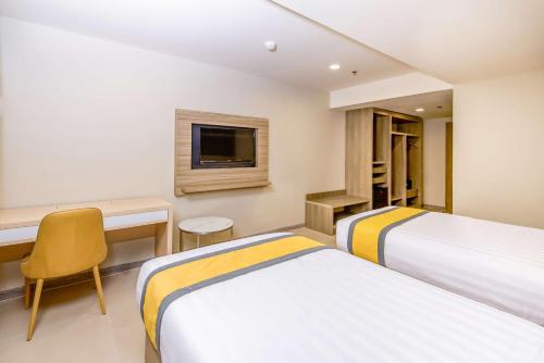 a hotel room with two beds and a desk and a tv at SureStay Plus by Best Western Cebu City in Cebu City