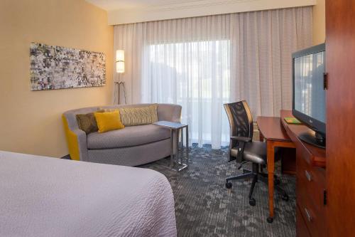 a hotel room with a bed and a couch and a desk at Sonesta Select Charlotte University Research Park in Charlotte