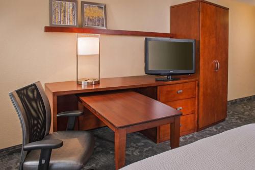 a hotel room with a desk with a television and a bed at Sonesta Select Charlotte University Research Park in Charlotte
