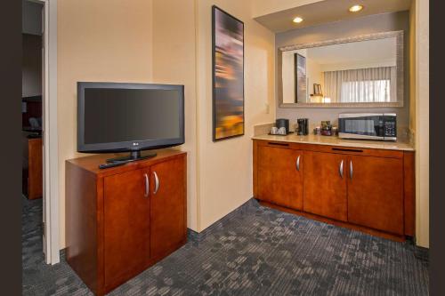 a room with a flat screen tv and a kitchen at Sonesta Select Charlotte University Research Park in Charlotte