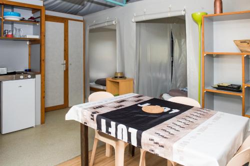 a dining room with a table and chairs and a kitchen at Parc du Charouzech in Salles-Curan