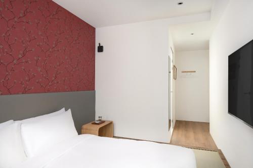 a bedroom with a white bed and a red wall at 禾淞津別邸 Kashotsu Bettei in Taichung