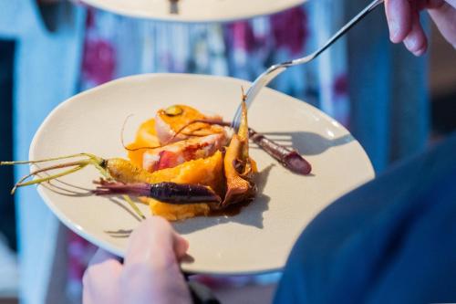 a person holding a plate of food on a fork at voco Brussels City North by IHG in Vilvoorde