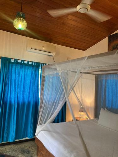 a bedroom with a canopy bed with blue curtains at Amba Kola Udawalawa in Udawalawe