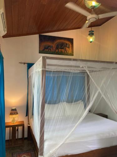 a bedroom with a bed with a mosquito net at Amba Kola Udawalawa in Udawalawe