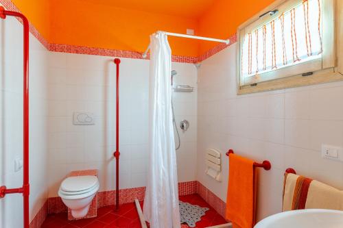 y baño de color naranja con aseo y ducha. en Tramonto al Rifugio Arcobaleno, en Popiglio