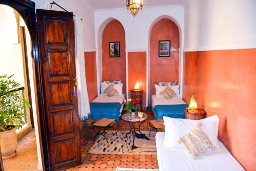 een woonkamer met 2 bedden en een tafel bij Dar Tuscia in Marrakesh