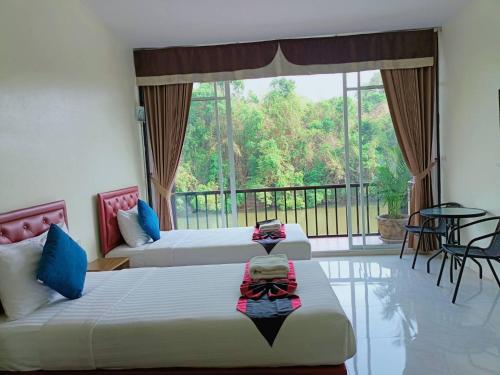 two beds in a room with a balcony at เพชรมณีกาญจน์ บีช รีสอร์ท in Ban Plai Huai Kaeng Riang
