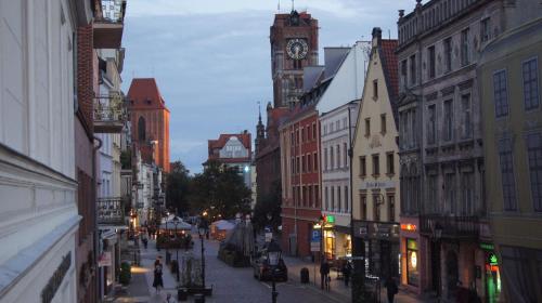 a city street with a clock tower in the distance at Apartamenty Street 18 in Toruń
