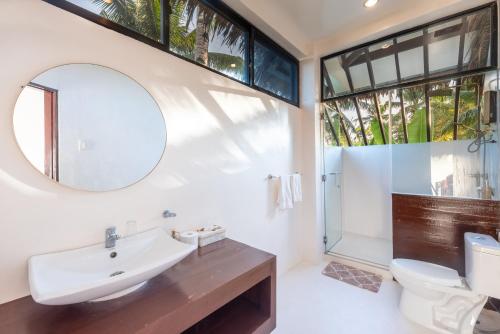 ein Badezimmer mit einem Waschbecken, einem WC und einem Spiegel in der Unterkunft Casa Bianca Siargao in General Luna