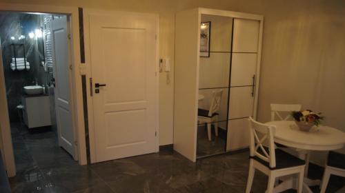 a room with a white door and a table and chair at Apartamenty Street 18 in Toruń