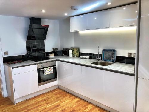 una cucina con armadi bianchi, lavandino e piano cottura di Crown House is a brand new development with unique features a Newbury
