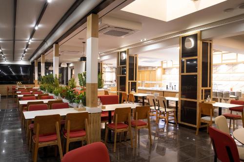 a restaurant with white tables and chairs and red chairs at Dafni Plus Hotel in Leptokaria