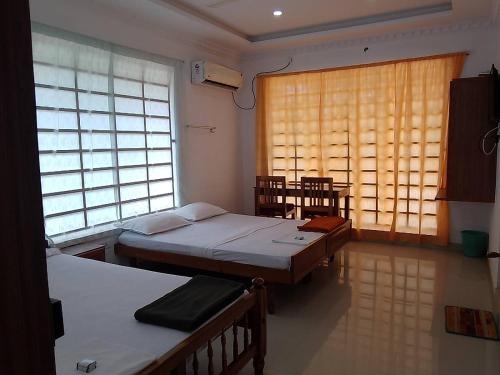 Habitación con 2 camas y ventana en Somatheertham Panchakarma Resort, en Kovalam