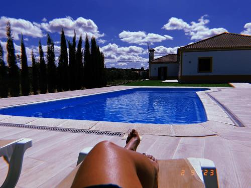 a person laying on a chair next to a swimming pool at Monte do Carapetal in Amareleja