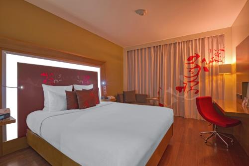 a bedroom with a large bed and a red chair at Novotel Bengaluru Outer Ring Road in Bengaluru