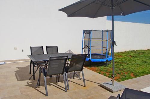 a table and chairs with an umbrella and a playground at Holiday house with private pool in village Šišan in Šišan