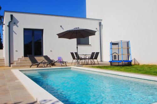 a pool with chairs and an umbrella next to a house at Holiday house with private pool in village Šišan in Šišan
