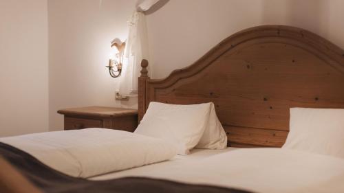 a bedroom with two beds with white sheets and a wooden headboard at Aparthotel Ansitz Felsenheim in Lermoos