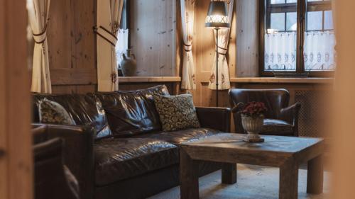 a living room with a brown leather couch and a table at Aparthotel Ansitz Felsenheim in Lermoos