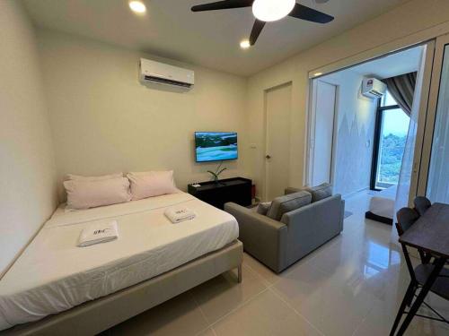 una camera con letto, divano e ventilatore a soffitto di BC@The Shore KK City View亚比城市景观 a Kota Kinabalu