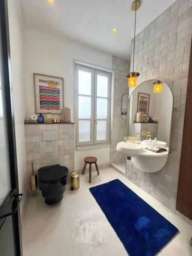 La salle de bains est pourvue de toilettes noires et d'un lavabo. dans l'établissement Le SeptièmeArt - Coeur de ville, à La Rochelle