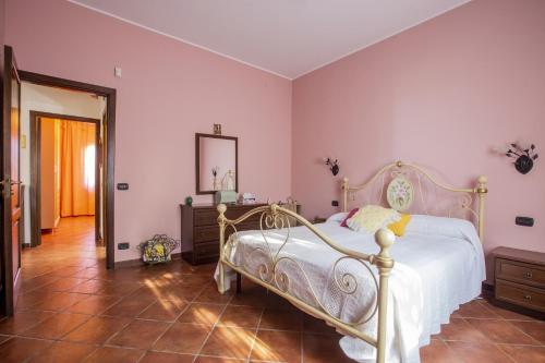 - une chambre avec un lit blanc et des murs roses dans l'établissement L' uliveto, à San Piero Patti