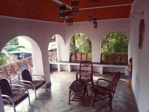 a room with chairs and tables and windows at Hosteller's in Varkala