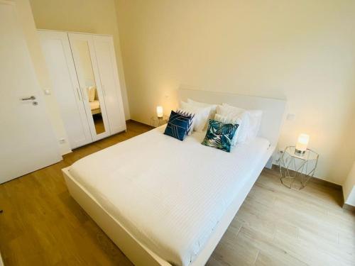 Una gran cama blanca con almohadas azules. en Luxury 2023 1 bedroom in city center with Free Parking-HOL1, en Luxemburgo