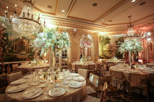 a dining room with tables and chairs and chandeliers at JW Marriott Essex House New York in New York
