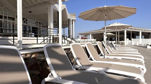 a row of white chairs and an umbrella on a patio at Caleta Dorada in Caleta De Fuste