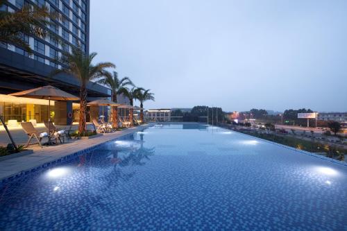 a large swimming pool with palm trees and a building at Holiday Inn Putian Xiuyu, an IHG Hotel in Putian