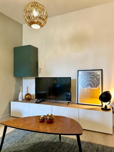 un salon avec une télévision et une table dans l'établissement LE PANCAUT- Chaleureux - Hyper Centre, à Mont-de-Marsan